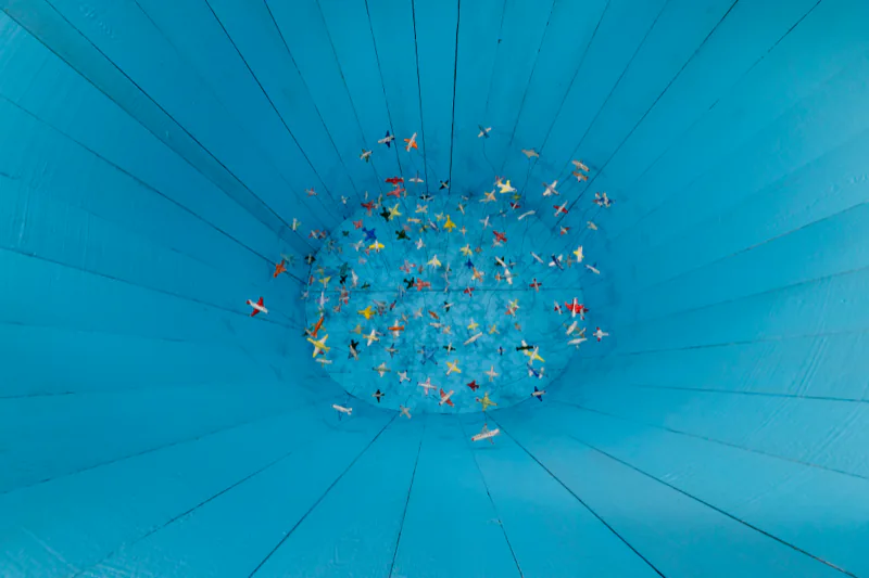 Countless airplanes hung inside a blue barrel